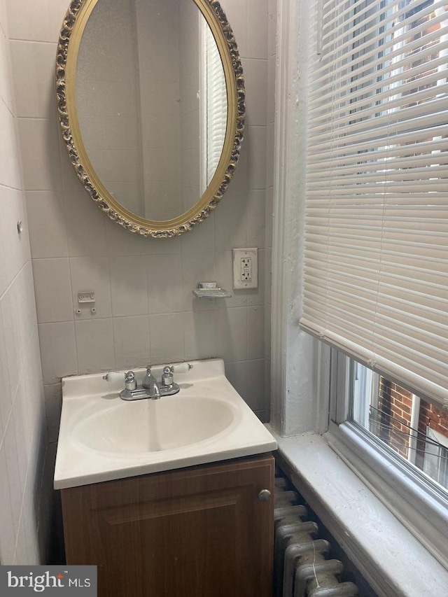 bathroom featuring tile walls, radiator, and vanity