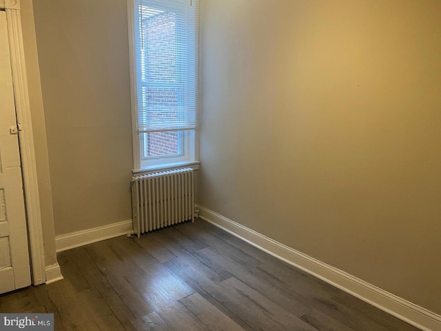 unfurnished room with a healthy amount of sunlight, dark wood-type flooring, and radiator heating unit