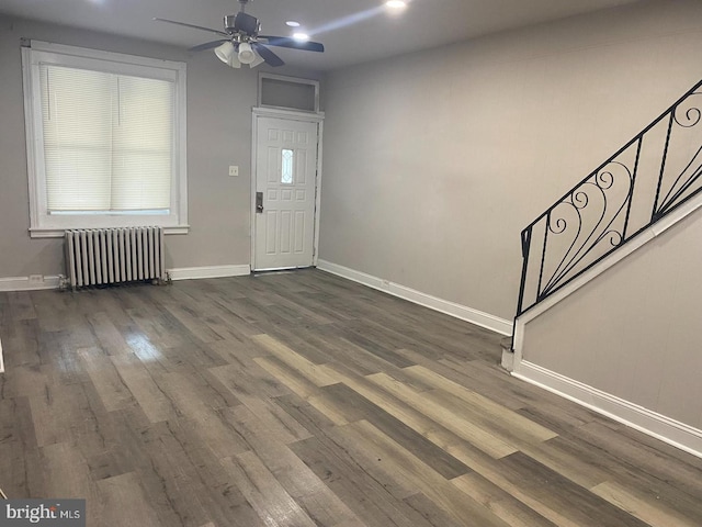 foyer entrance featuring dark wood-type flooring, ceiling fan, and radiator heating unit