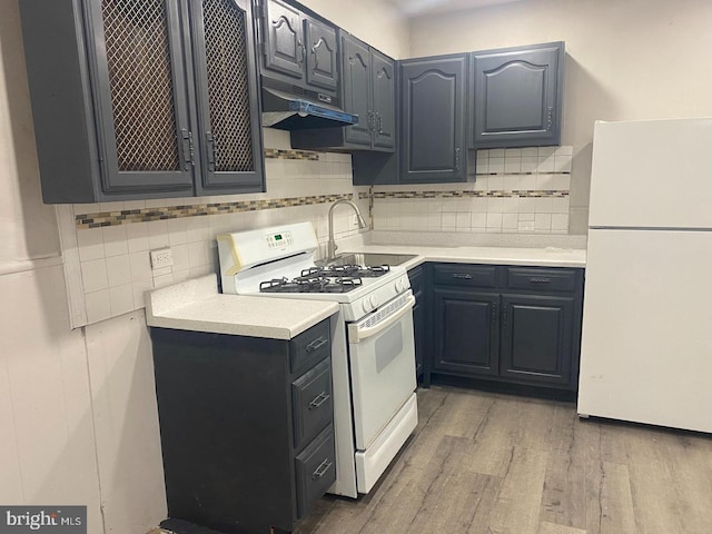 kitchen with white appliances, tasteful backsplash, sink, and hardwood / wood-style flooring