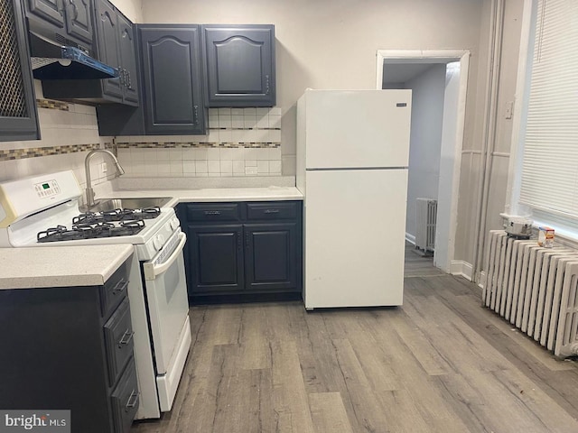 kitchen featuring white appliances, radiator heating unit, backsplash, and light hardwood / wood-style flooring