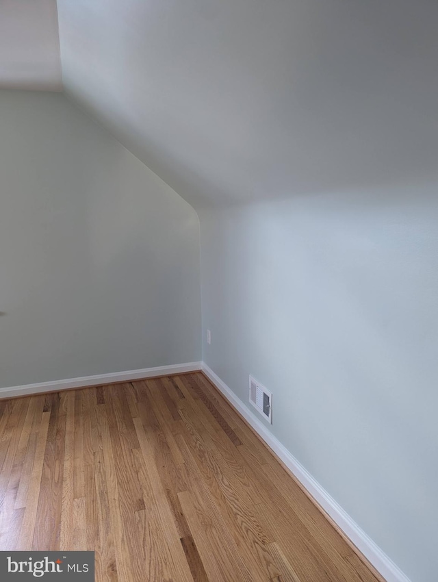 additional living space featuring light wood-type flooring and vaulted ceiling