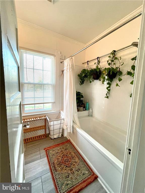 bathroom featuring shower / tub combo with curtain and crown molding