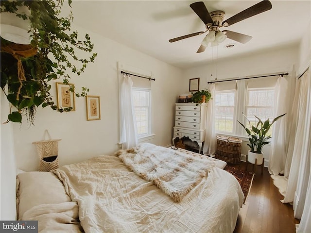 bedroom featuring ceiling fan, multiple windows, and dark hardwood / wood-style floors