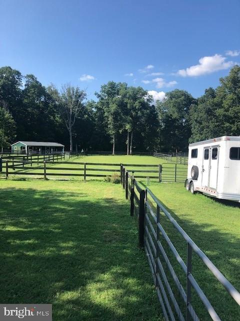 surrounding community with a yard, a rural view, and an outdoor structure