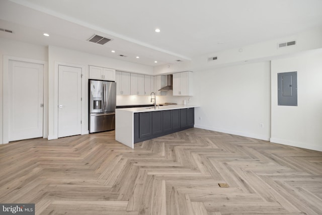 kitchen featuring wall chimney exhaust hood, sink, white cabinetry, stainless steel fridge, and electric panel