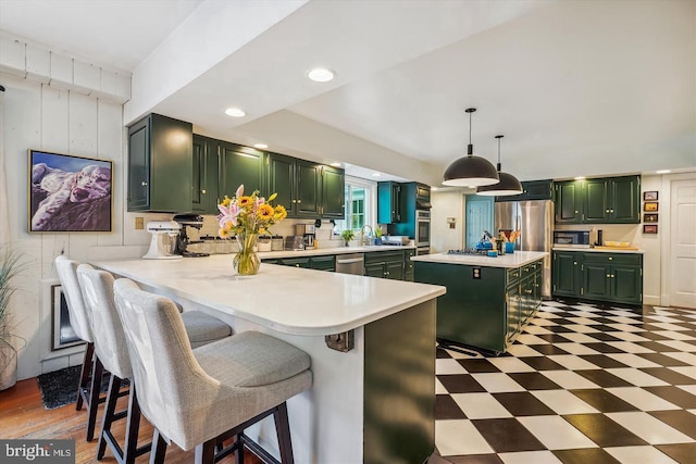 kitchen featuring green cabinets, pendant lighting, kitchen peninsula, and appliances with stainless steel finishes