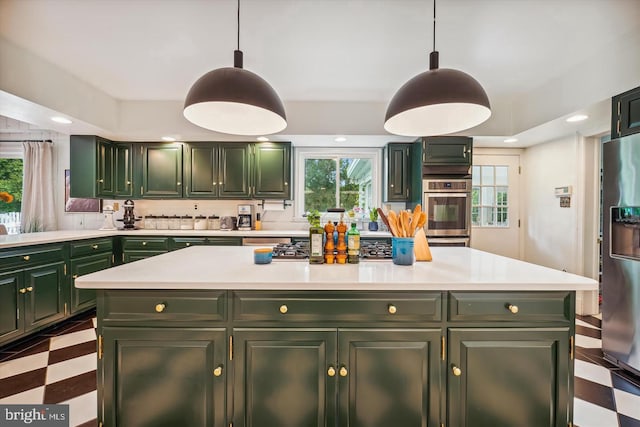 kitchen with stainless steel fridge, hanging light fixtures, and green cabinetry