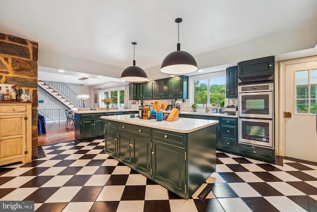 kitchen featuring a kitchen island, double oven, pendant lighting, and sink