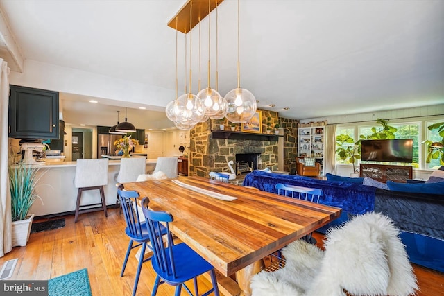 dining area featuring light wood-type flooring and a stone fireplace