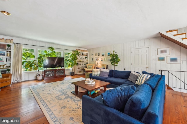 living room with built in features, wood walls, and hardwood / wood-style floors