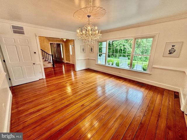 empty room with an inviting chandelier, crown molding, and hardwood / wood-style flooring