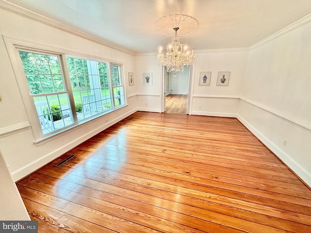 unfurnished dining area with ornamental molding, light wood-type flooring, and a notable chandelier