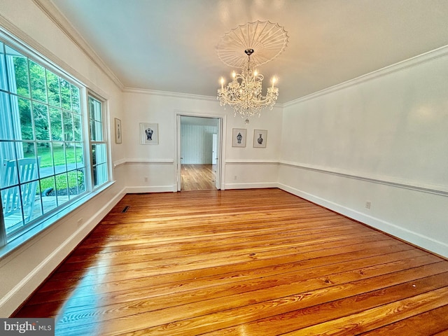 interior space with wood-type flooring, ornamental molding, a chandelier, and plenty of natural light