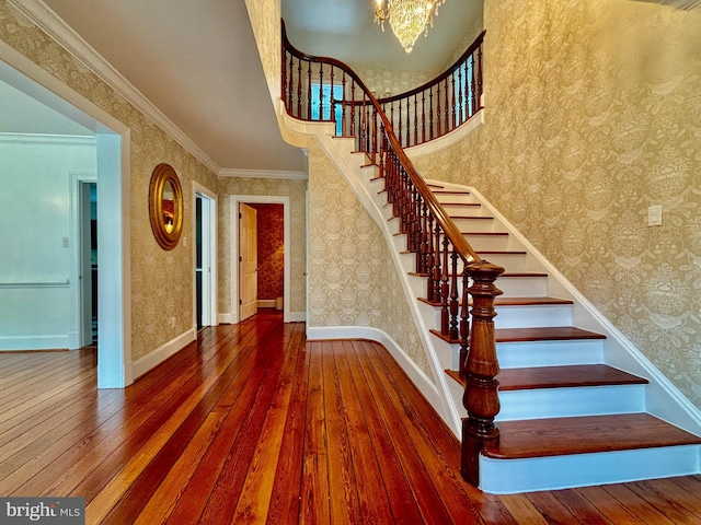 stairs with hardwood / wood-style floors, crown molding, and a chandelier