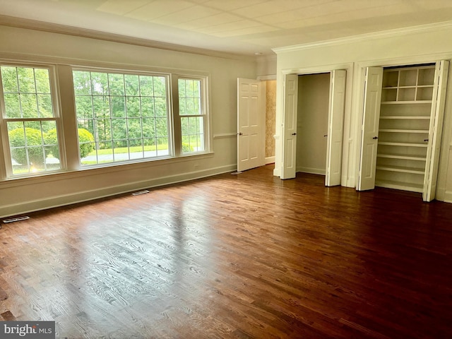 unfurnished bedroom with multiple closets, dark wood-type flooring, and ornamental molding