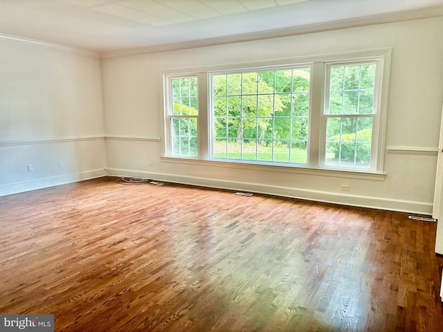 unfurnished room featuring ornamental molding, a wealth of natural light, and hardwood / wood-style flooring