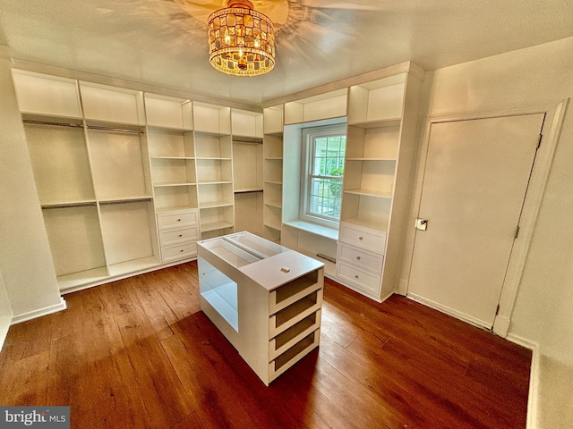 spacious closet featuring an inviting chandelier and dark hardwood / wood-style floors