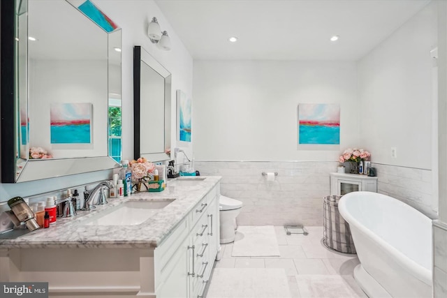 bathroom with toilet, a bathtub, tile patterned flooring, tile walls, and vanity