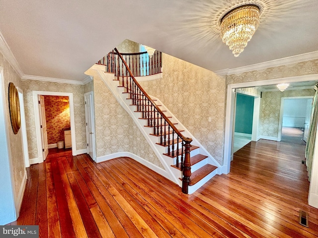 stairs with a chandelier, hardwood / wood-style floors, and crown molding