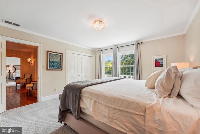 bedroom featuring a closet, crown molding, and dark carpet