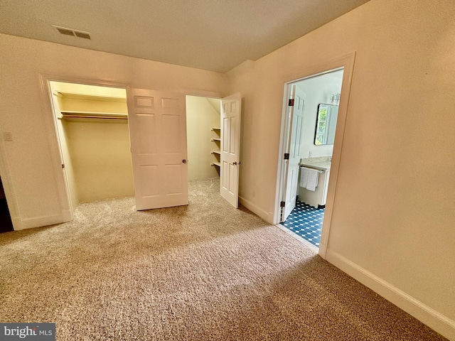 unfurnished bedroom with ensuite bathroom, a closet, and carpet flooring