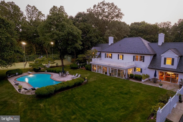 back of house featuring a balcony, a patio, and a yard