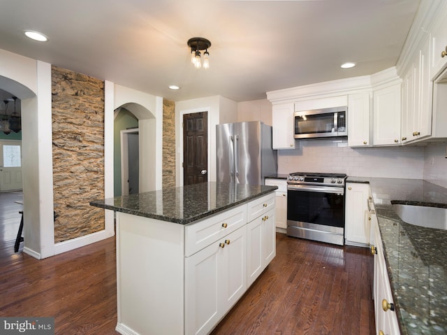 kitchen featuring appliances with stainless steel finishes, a center island, white cabinets, and dark stone counters