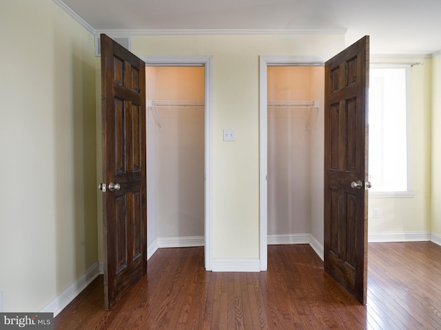 unfurnished bedroom featuring dark hardwood / wood-style flooring, crown molding, and a closet