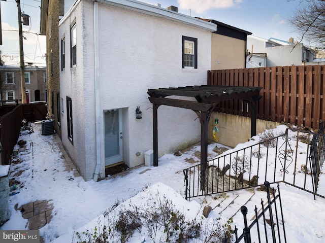 snow covered property featuring a pergola and central air condition unit