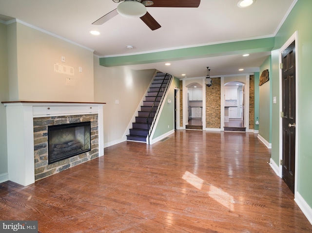 unfurnished living room featuring hardwood / wood-style flooring, ornamental molding, ceiling fan, and a fireplace