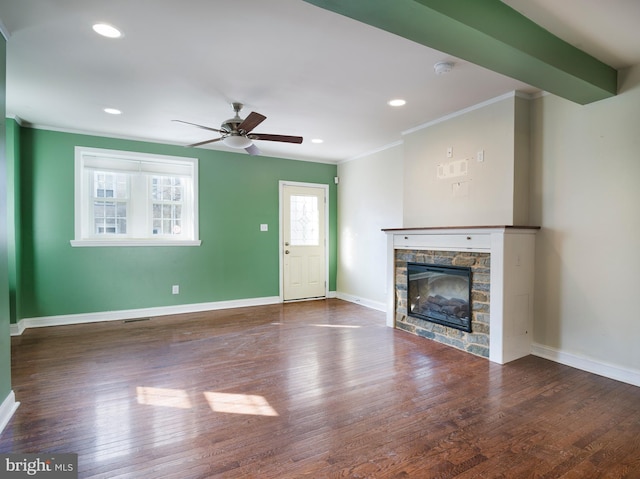 unfurnished living room with a stone fireplace, dark wood-type flooring, ornamental molding, and ceiling fan