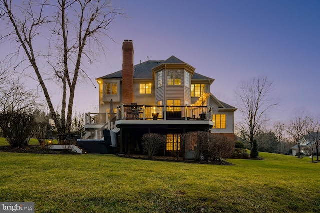 back house at dusk with a lawn and a deck