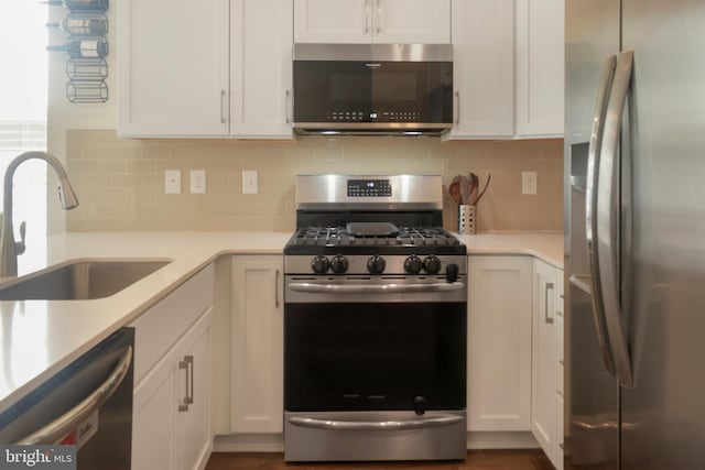 kitchen with sink, backsplash, white cabinetry, and appliances with stainless steel finishes