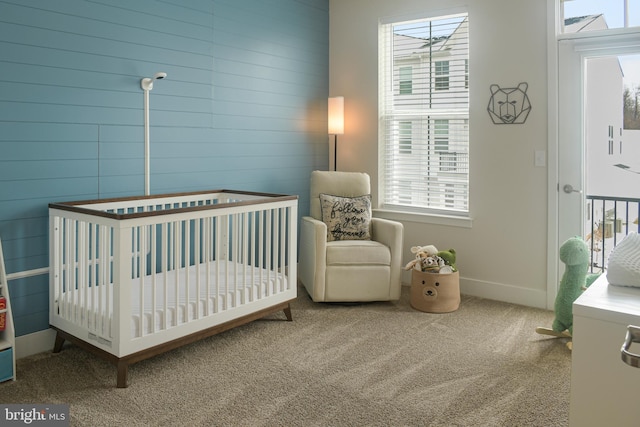 carpeted bedroom featuring a crib and multiple windows