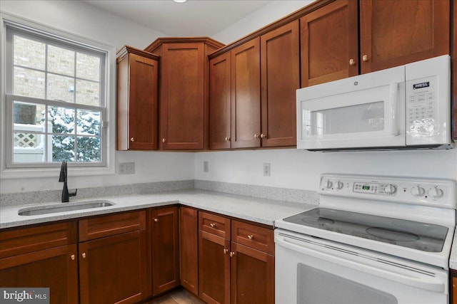 kitchen featuring sink, white appliances, and light stone countertops