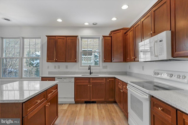 kitchen featuring light stone counters, sink, white appliances, and light wood-type flooring