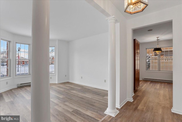 interior space featuring wood-type flooring, baseboard heating, and decorative columns