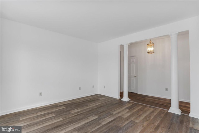 spare room featuring decorative columns and dark hardwood / wood-style flooring