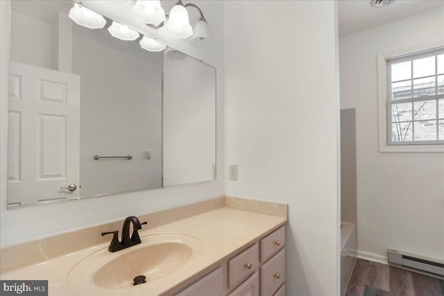 bathroom with vanity, a bath, a baseboard heating unit, and hardwood / wood-style floors