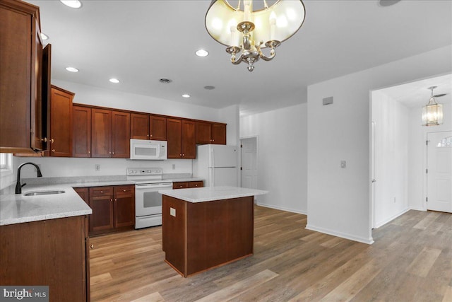 kitchen with white appliances, a center island, sink, hanging light fixtures, and a chandelier