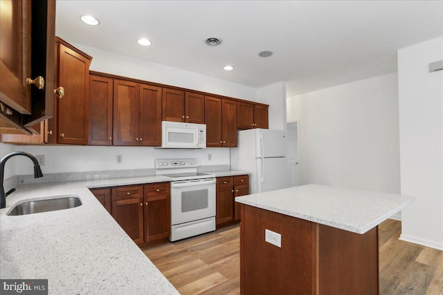 kitchen featuring sink, light stone countertops, white appliances, a center island, and light hardwood / wood-style floors