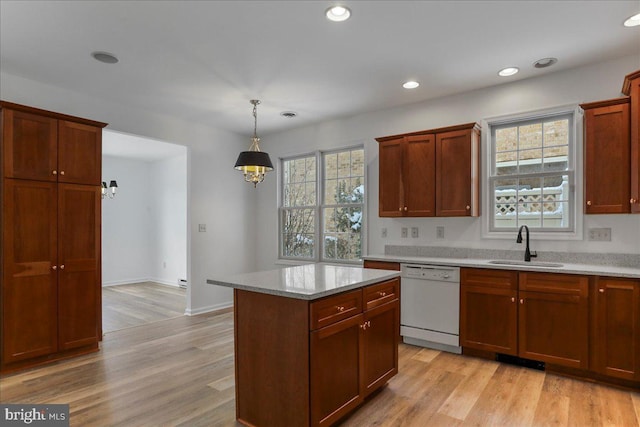 kitchen featuring pendant lighting, a wealth of natural light, light hardwood / wood-style floors, sink, and white dishwasher