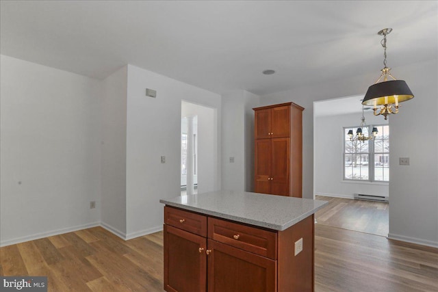 kitchen featuring decorative light fixtures, a baseboard heating unit, a center island, and light wood-type flooring