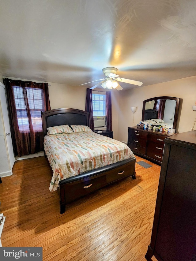 bedroom with cooling unit, ceiling fan, and light hardwood / wood-style flooring