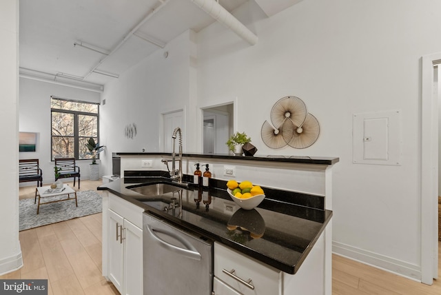 kitchen featuring sink, dishwasher, white cabinets, and light wood-type flooring