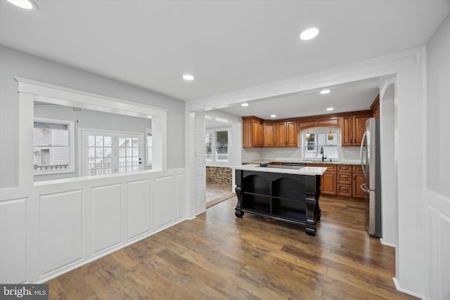 kitchen featuring sink, a kitchen bar, stainless steel refrigerator, a kitchen island, and dark hardwood / wood-style flooring