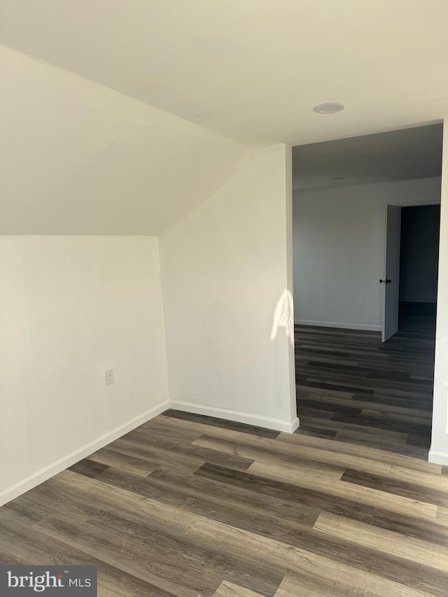 additional living space featuring dark wood-type flooring and lofted ceiling