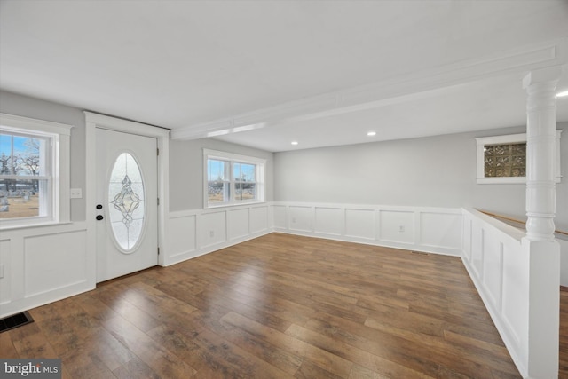 foyer entrance with decorative columns and dark hardwood / wood-style floors