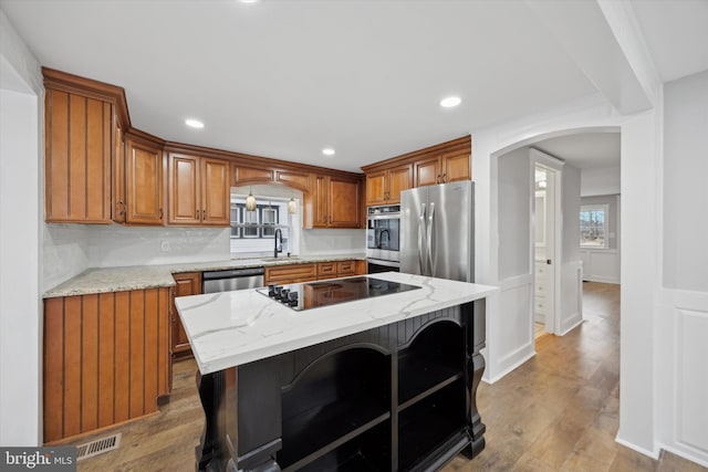 kitchen with sink, light stone counters, a kitchen breakfast bar, a kitchen island, and appliances with stainless steel finishes